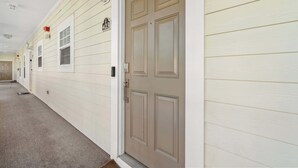 A hallway with a beige door, a number '423' sign, and a window. - "Seas the Day" at barefoot resort in Ironwood (North Myrtle Beach)