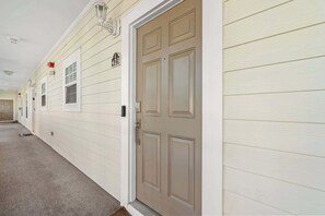 A hallway with a beige door, a number '423' sign, and a window. - "Seas the Day" at barefoot resort in Ironwood (North Myrtle Beach)