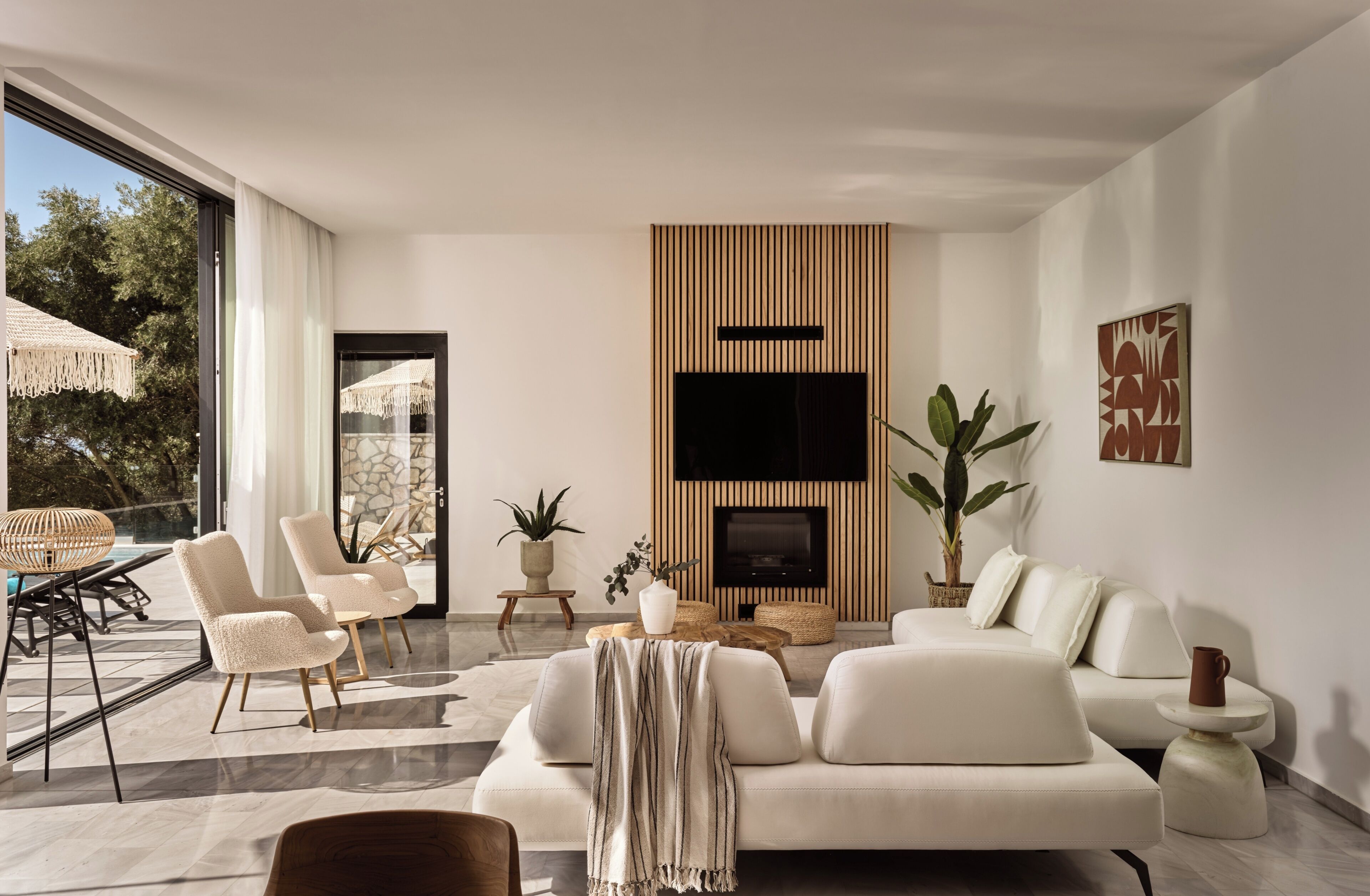 A modern living room with a sofa, chairs, a TV, and a fireplace.
