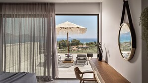 Un dormitorio con una ventana grande, una cama, un escritorio, una silla y vistas al mar.