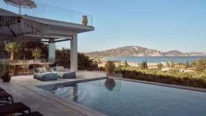 Un área de piscina moderna al aire libre con vistas al mar y a las montañas.
