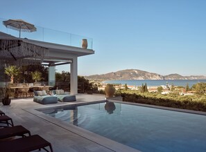 Ein moderner Poolbereich im Freien mit Blick auf das Meer und die Berge.