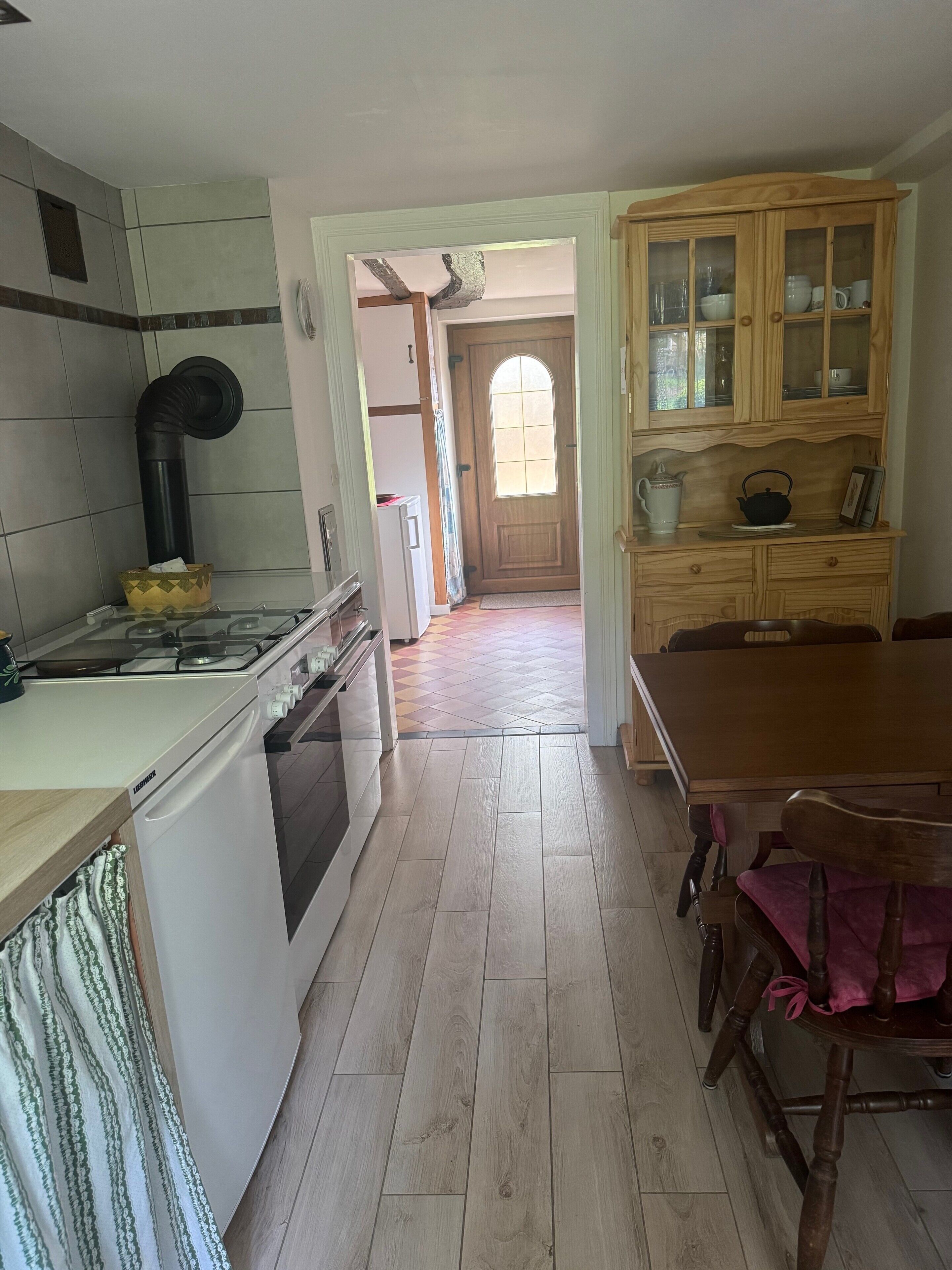 A kitchen with a stove, oven, and cabinets, leading to a dining area with a table and chairs.