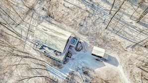An aerial view of a snow-covered area with a large truck parked on a road.