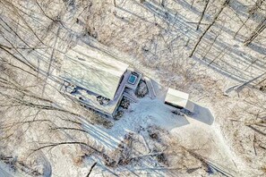 An aerial view of a snow-covered area with a large truck parked on a road. - Elevated mountain-view cabin with private hot tub, 2 decks, firepit, & grill (Cullowhee)