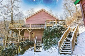 A wooden cabin with a balcony, a staircase, and a snow-covered landscape. - Elevated mountain-view cabin with private hot tub, 2 decks, firepit, & grill (Cullowhee)