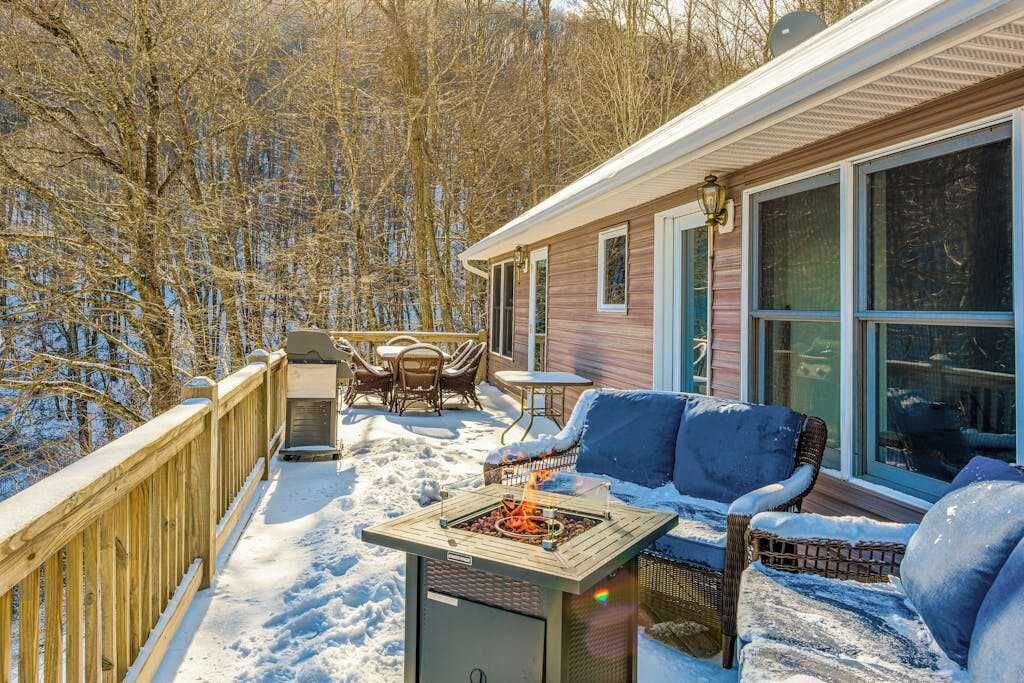 Une terrasse dotée de mobilier d’extérieur, d’un foyer et d’une maison avec de grandes fenêtres.