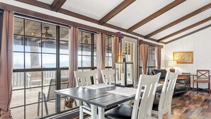 Un espace repas comprenant une table et des chaises, de grandes fenêtres et une vue sur l’extérieur.