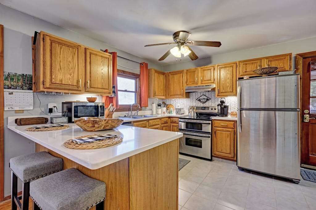 A kitchen with wooden cabinets, a central island, a refrigerator, and a ceiling fan.