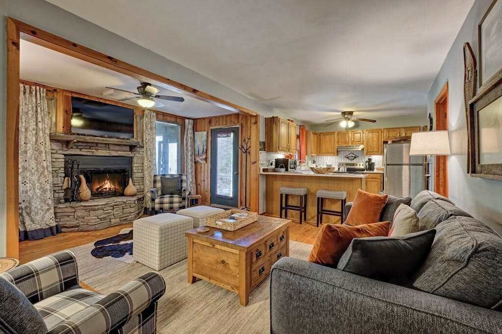 A cozy living room with a fireplace, a dining area, and a kitchen.