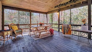 A covered outdoor area with a wooden deck, a table with chairs, and a bench.