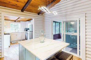 A modern kitchen with white cabinets, a marble countertop, and a hanging light fixture. - Mountain Dreams (Bryson City)
