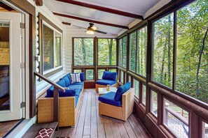 A covered porch with wicker furniture, large windows, and a ceiling fan. - Mountain Dreams (Bryson City)