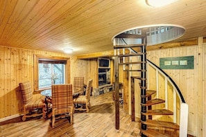 A wooden interior with a spiral staircase, wooden walls, and a fireplace. - Mountain Dreams (Bryson City)