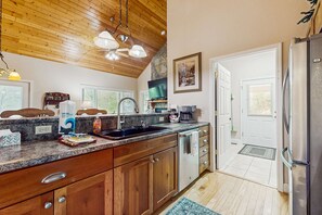 Eine Küche mit Holzausstattung, einer Granitabdeckung, einer Spüle und einem Kühlschrank.