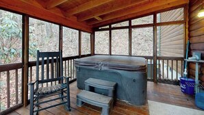 A wooden deck with a hot tub, a bench, and a step stool. - Hawks Landing (Sylva)