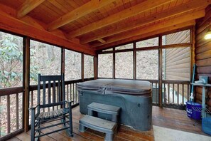 Eine Holzterrasse mit einem Whirlpool, einer Bank und einem Trittkasten.