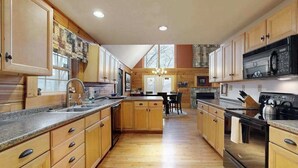 A spacious kitchen with wooden cabinets, a central island, and a dining area. - Hawks Landing (Sylva)