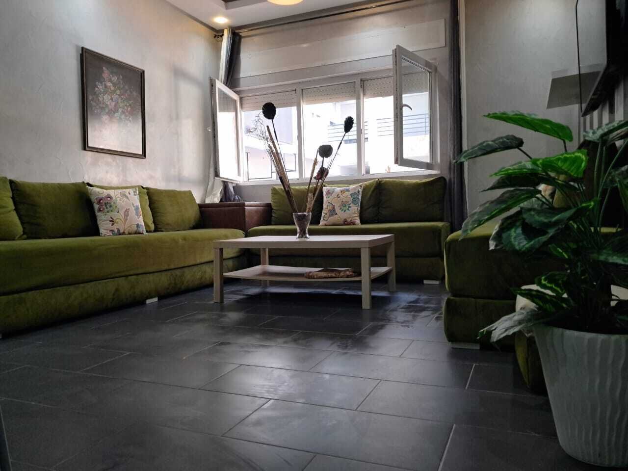 A living room with a green sofa, a coffee table, and a potted plant.