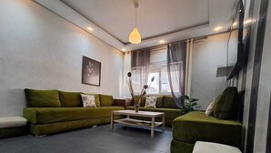 Een woonkamer met een zithoek, een salontafel en een hanglamp.