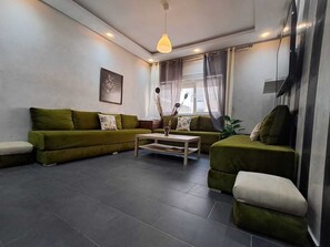 Ein Wohnzimmer mit einer Sofagarnitur, einem Couchtisch und einer Hängelampe.