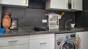 Een compacte keuken met een gasfornuis, een wasmachine en een klein spoelgedeelte.