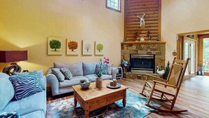 Una sala de estar acogedora con chimenea, un sofá, una mesa de centro y un sillón mecedora.