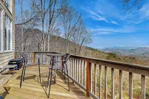 Eine Holzterrasse mit Gartenmöbeln, einem Geländer und Blick auf die umliegende Landschaft.