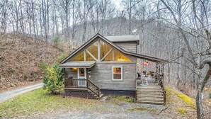 Eine Hütte mit Veranda, Treppe und Blick auf den umliegenden Wald.