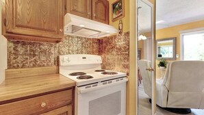 A kitchen with wooden cabinets, a white stove, and a beige chair.