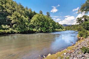 A river surrounded by dense forest and rocky terrain. - Country Cottage (Sylva)