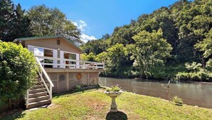 A house with a balcony, a staircase, and a river in the background.