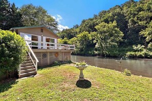 A house with a balcony, a staircase, and a river in the background. - Country Cottage (Sylva)