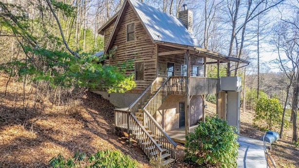Un rustico chalet con tetto in metallo, scala in legno e veranda.