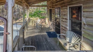 Una baita di legno con un portico, due poltrone Adirondack e una zona riparata.