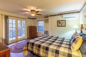 Un dormitorio con cama, ventilador de techo, cómoda, ventana y puerta.