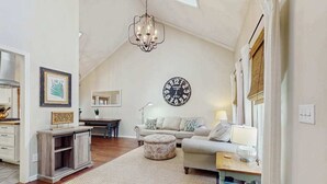 A cozy living room with a chandelier, a round wall clock, a sofa, and a coffee table. - Ripple Run (Sylva)