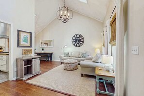 Ein gemütliches Wohnzimmer mit einer Kronleuchter, einer runden Wanduhr, einem Sofa und einem Couchtisch.