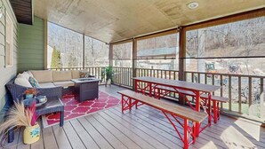 A covered outdoor deck with a sofa, a table, and benches. - Ripple Run (Sylva)