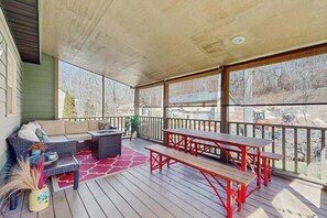 Eine überdachte Terrasse mit einer Sitzecke, einem Tisch und Bänken.