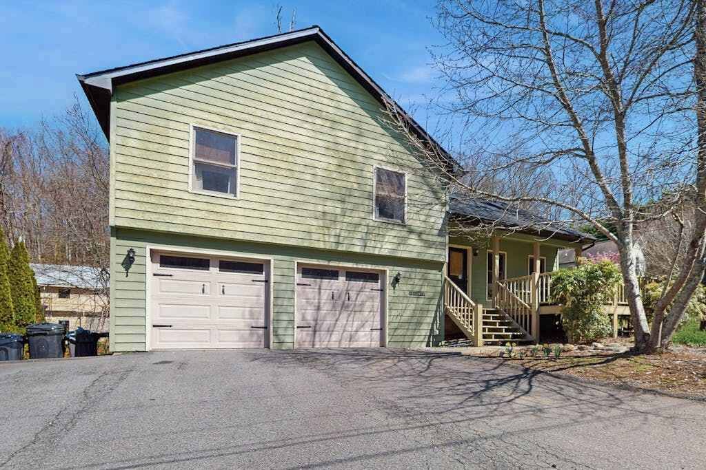 A two-story house with a garage, a front porch, and a staircase leading to the entrance.