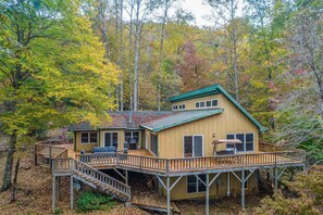 Une cabane avec une terrasse, une cheminée et un porche.
