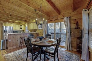 Ein Holzblockhaus-Innenraum mit Essbereich, Küche und großen Fenstern.