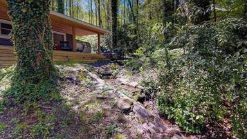 Une cabane dotée d’une terrasse en bois, entourée d’une forêt dense.