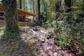 Eine Holzhütte mit einer Holzterrasse, umgeben von dichtem Wald.