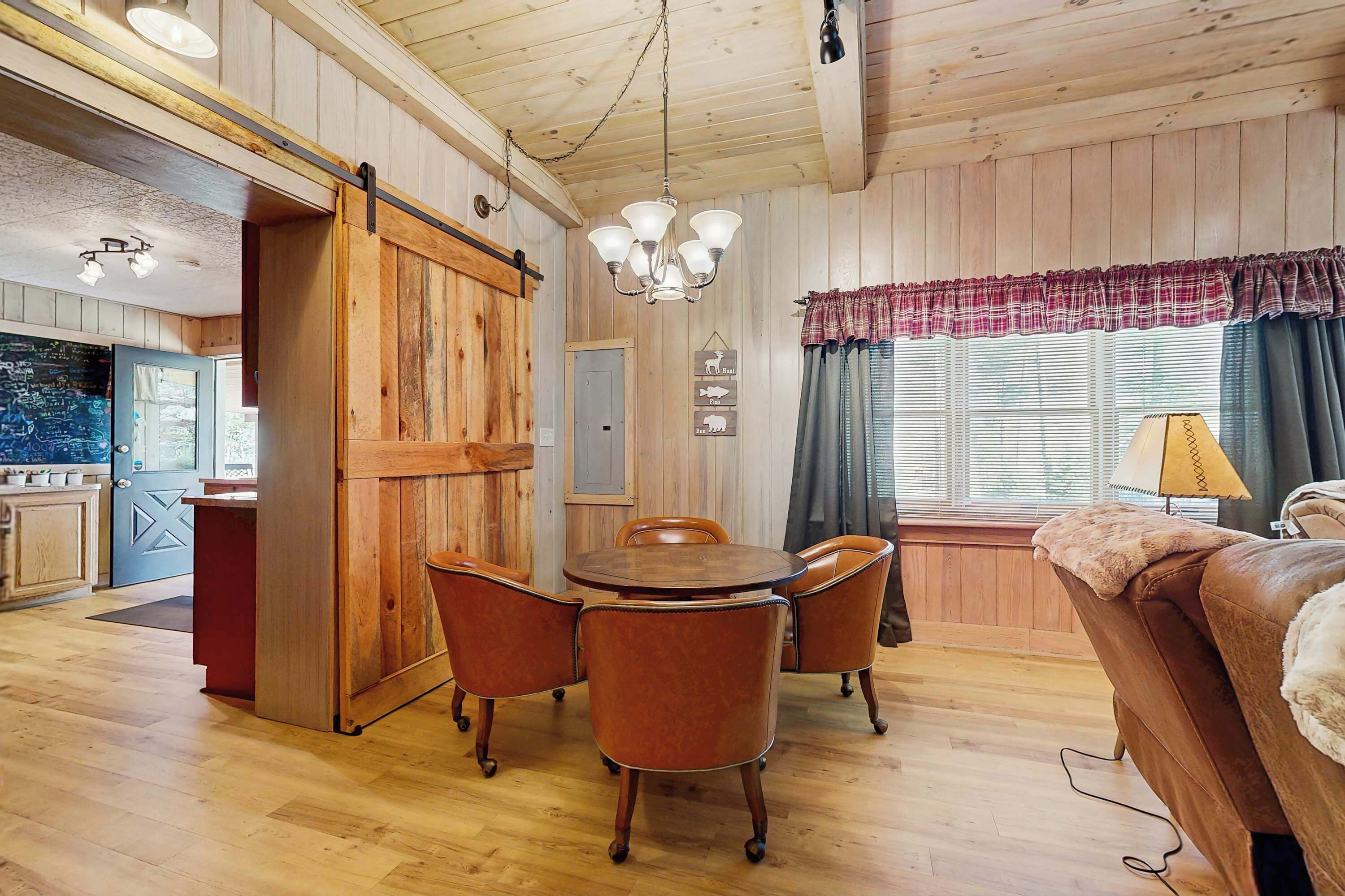 Un interior de madera con una mesa de comedor, sillas, un sofá y una zona de cocina.