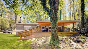 A cabin with a wooden deck, a staircase, and a covered porch.