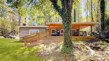 Une cabane dotée d’une terrasse en bois, d’un escalier et d’un porche couvert.