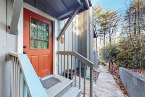 A house with a red door, a wooden staircase, and a stone pathway leading to a garden. - The Cottage on Chowan (Highlands)