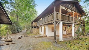 Eine rustikale Holzhütte mit einer Holzterrasse, Steinmauerwerk und einer Veranda.
